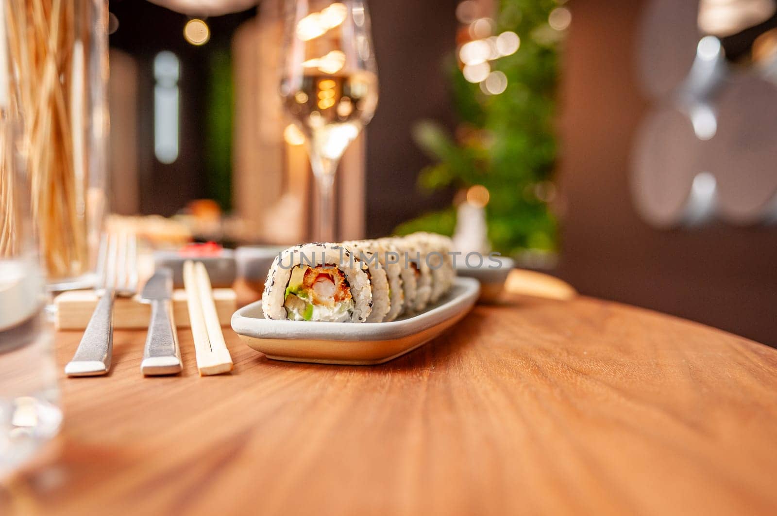 Sushi roll with cream cheese, sesame seeds and green flying fish caviar on a plate close-up. High quality photo