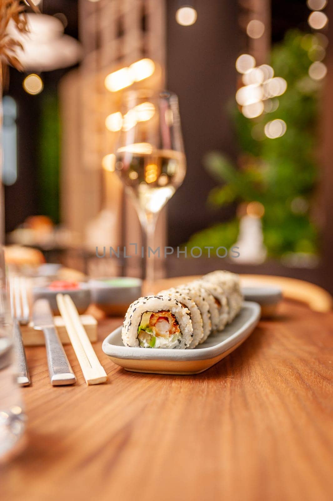 Sushi roll with cream cheese, sesame seeds and green flying fish caviar on a plate close-up. High quality photo