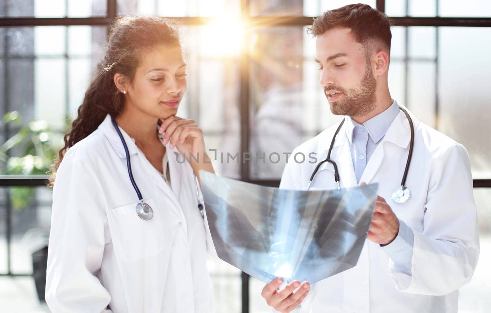 Two busy doctors working with papers and x-rays in hospital lobby