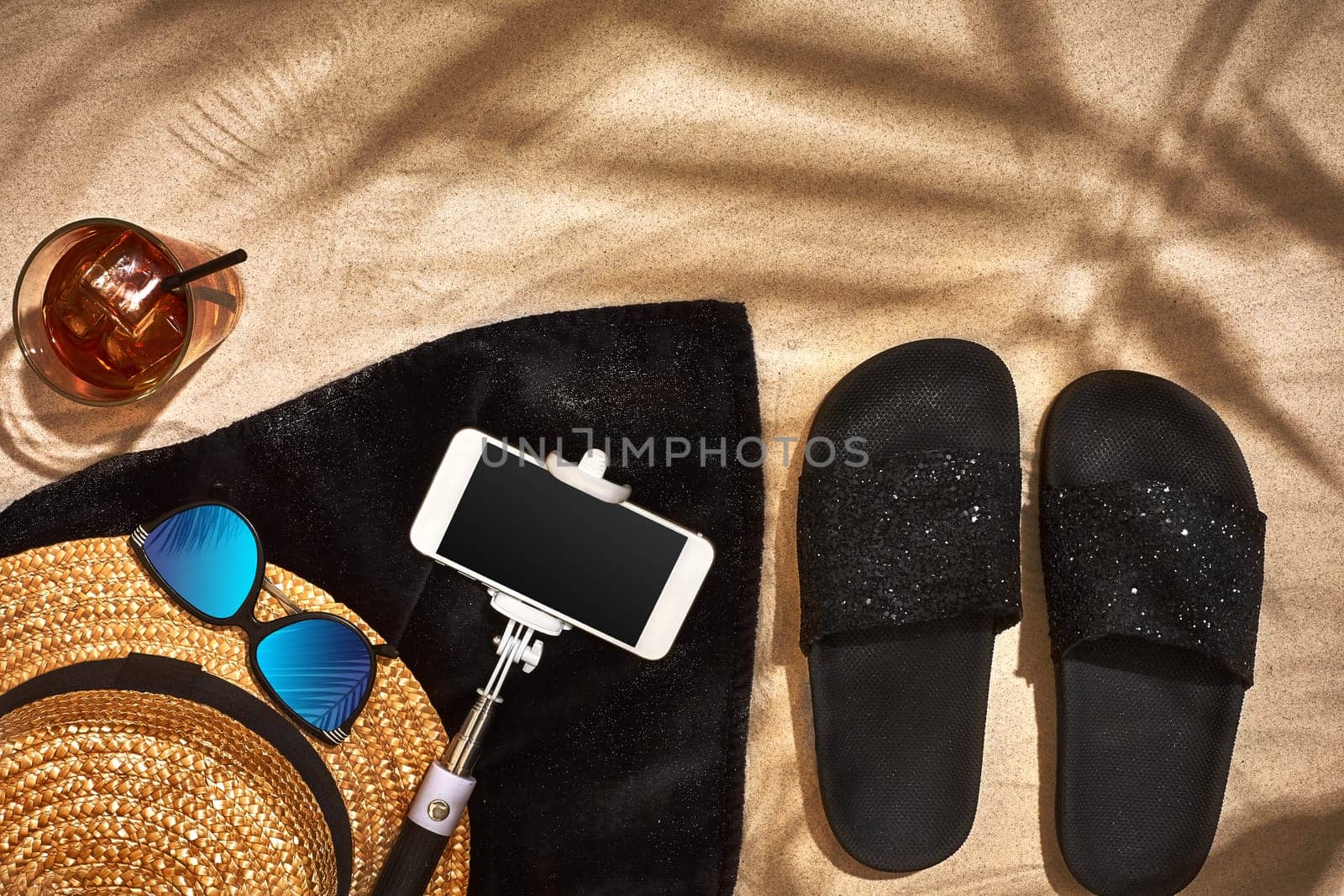 Top view of summer accessories on sandy beach. Shadow from a palm leaf. Still life. Copy space. Flat lay