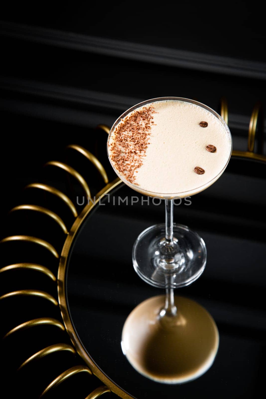 iced latte with foam in a martini glass on a dark background side view