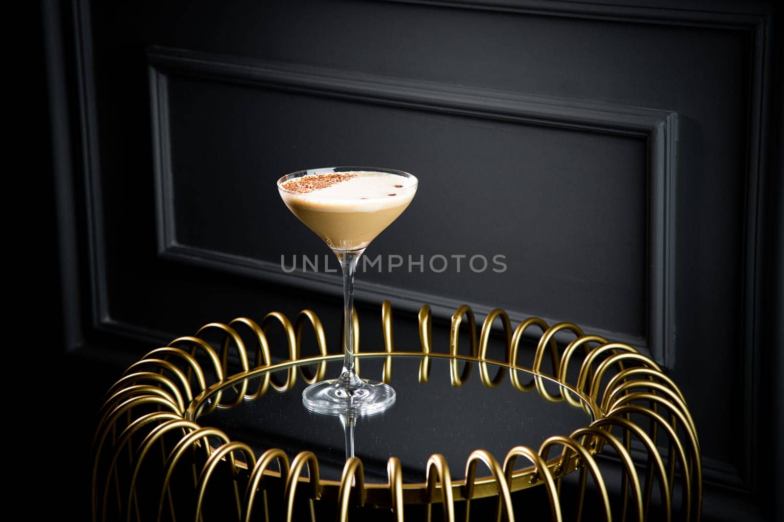 iced latte with foam in a martini glass on a dark background side view