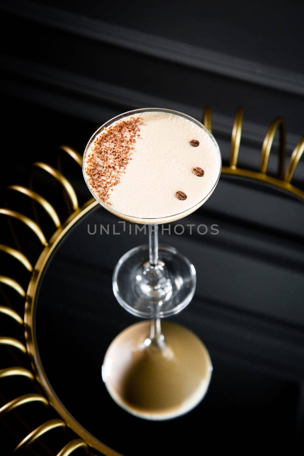 iced latte with foam in a martini glass on a dark background side view