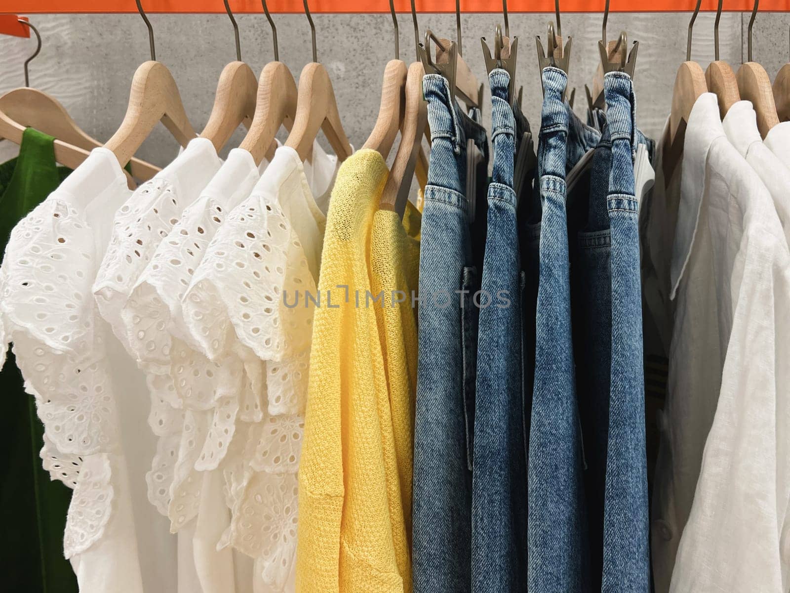 Blouses, sweaters, jeans hang on a hanger at the store