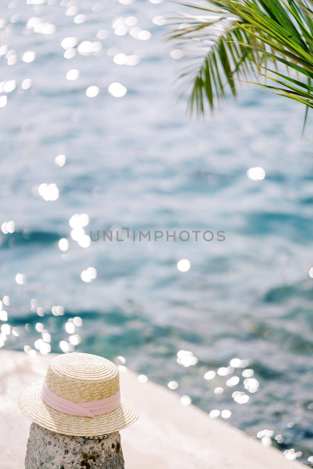 Woman straw hat lies on a bollard on a pier by the sea. High quality photo