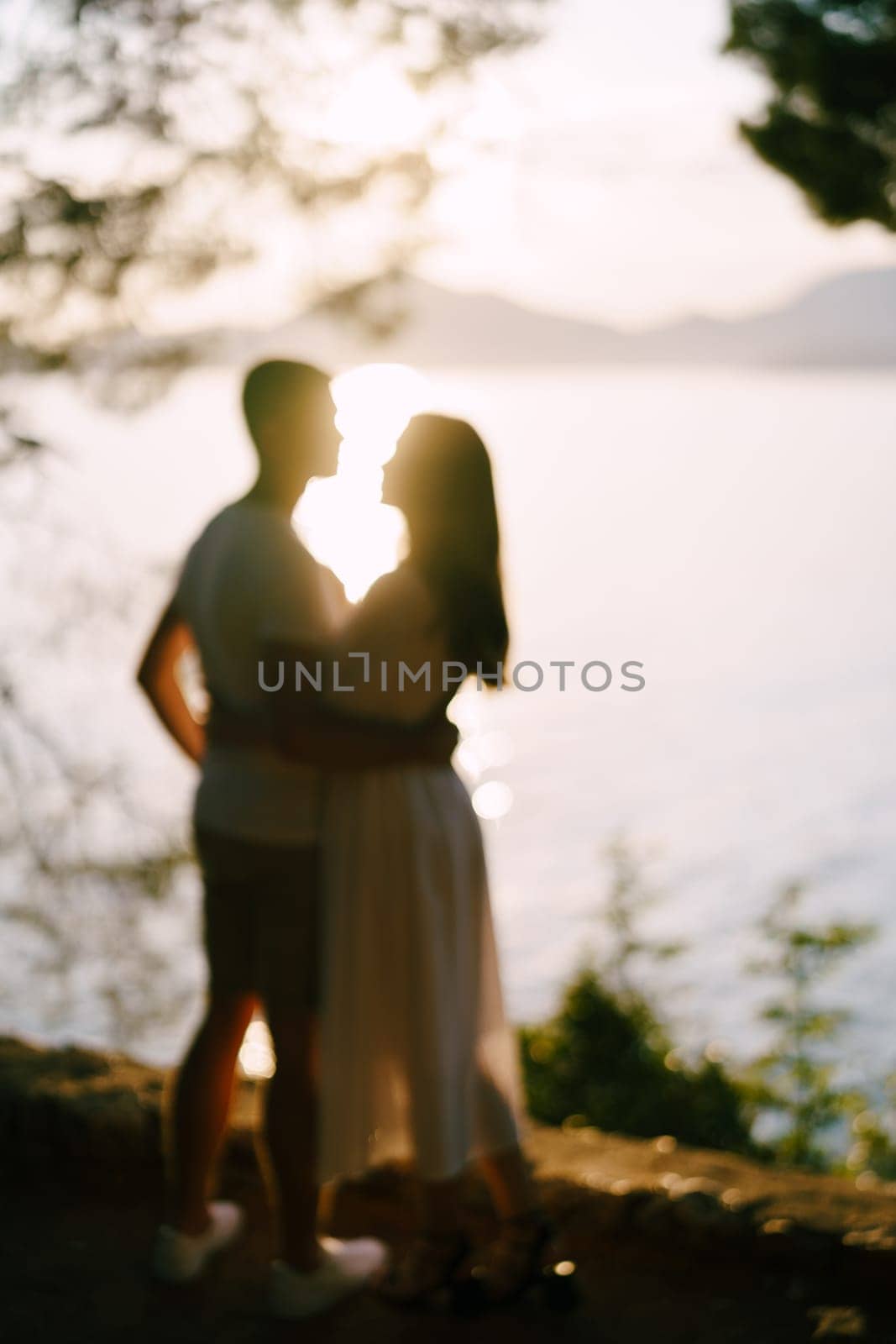 Man hugs woman by the sea against the backdrop of mountains. Blur by Nadtochiy
