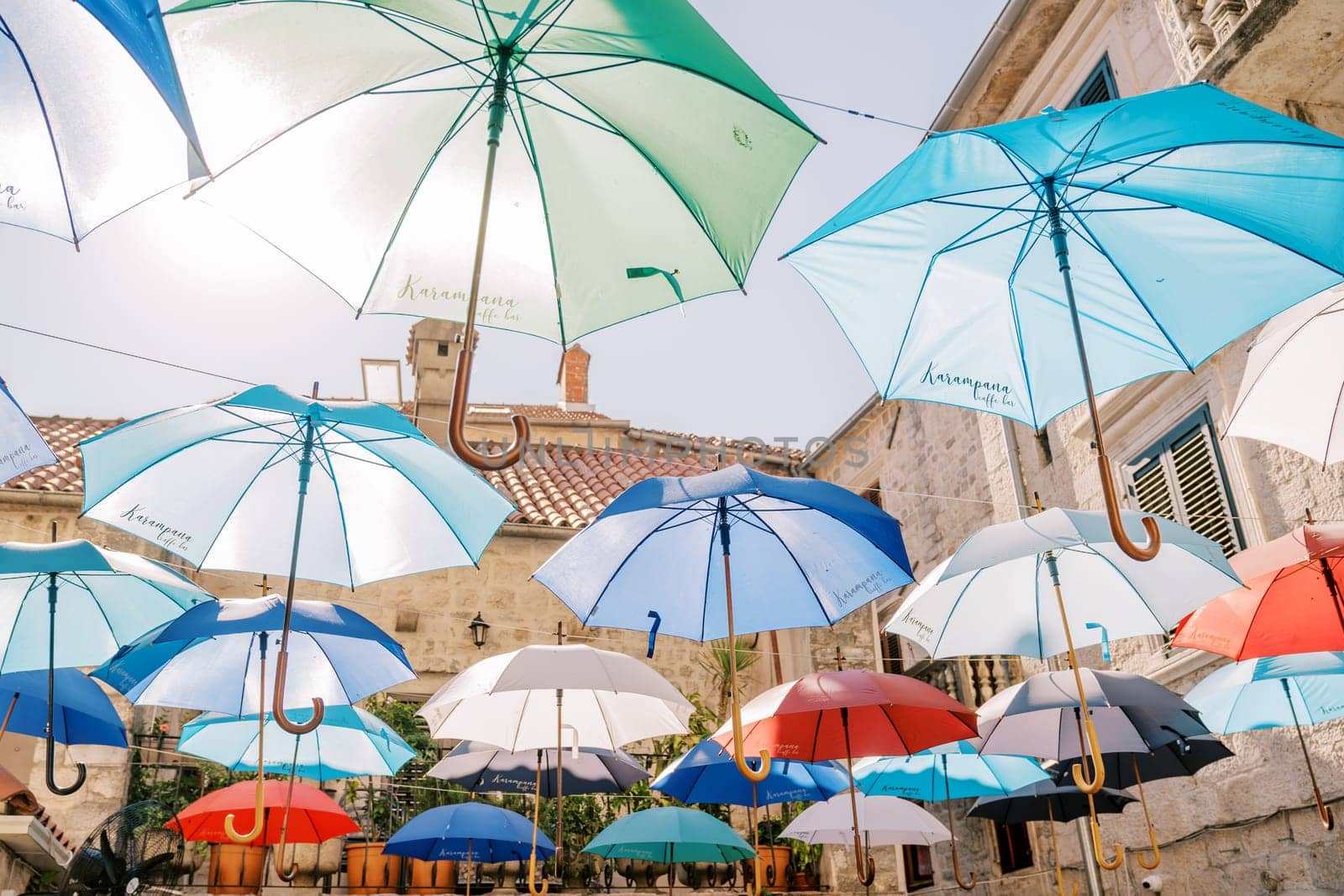 Colorful umbrellas hang on ropes above the street near old houses. High quality photo