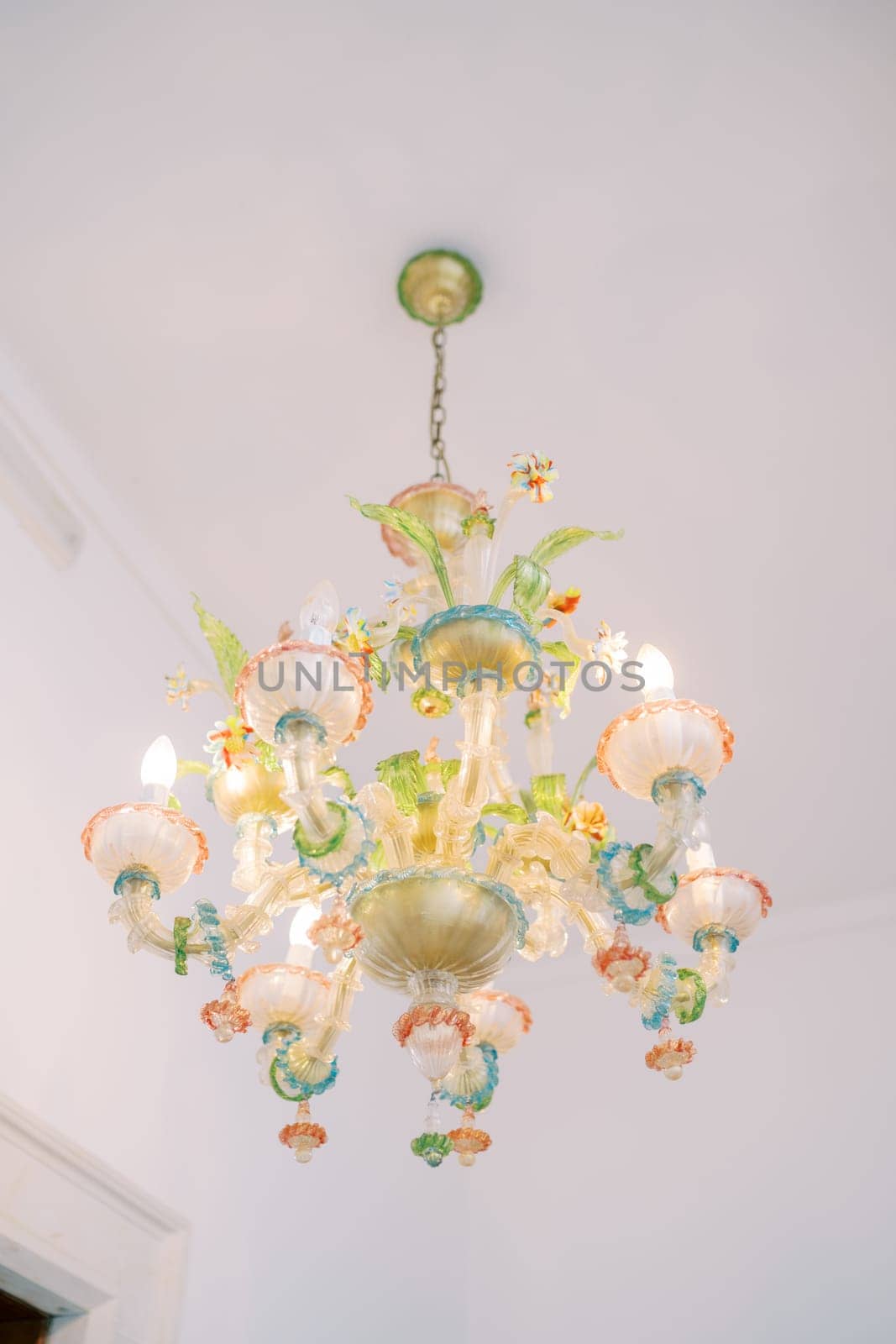 Colorful chandelier with floral decoration hanging on the ceiling of the room. High quality photo