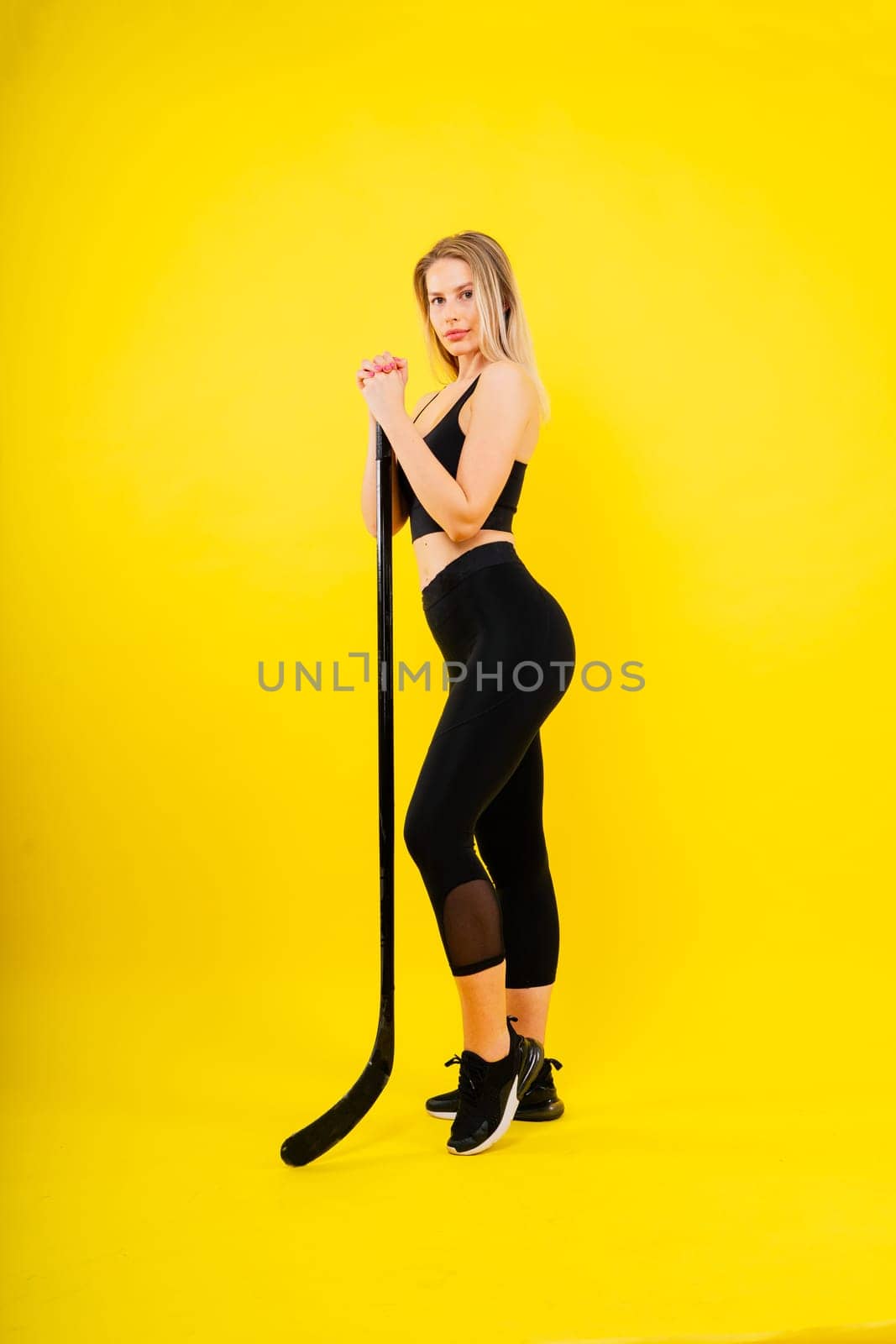 Ice hockey fan female in sports wear with hockey stick in a studio