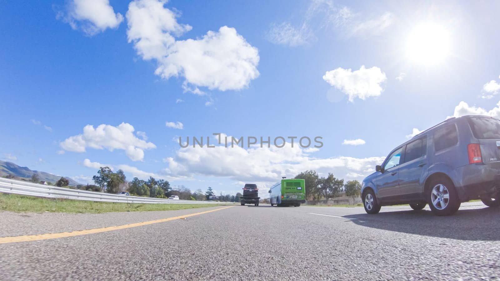 Santa Maria, California, USA-December 6, 2022-On a clear winter day, a car smoothly travels along Highway 101 near Santa Maria, California, under a brilliant blue sky, surrounded by a blend of greenery and golden hues.