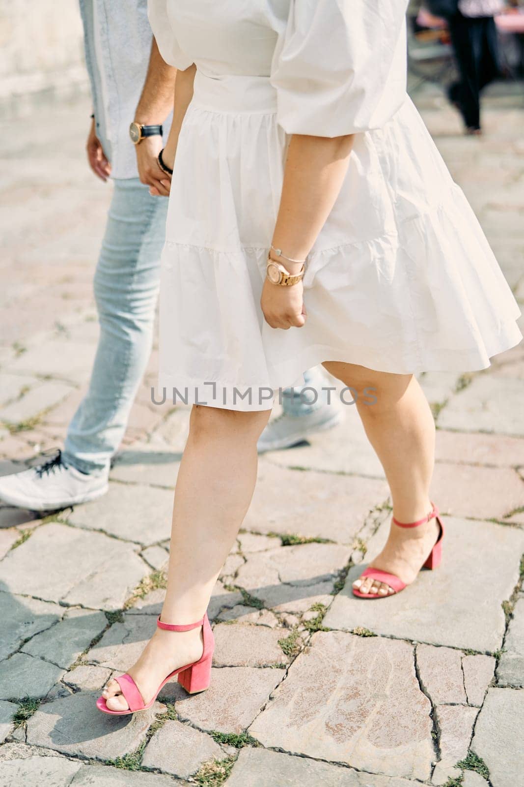 Man and woman walk along the paving stones, holding hands. Cropped. Faceless. Side view. High quality photo