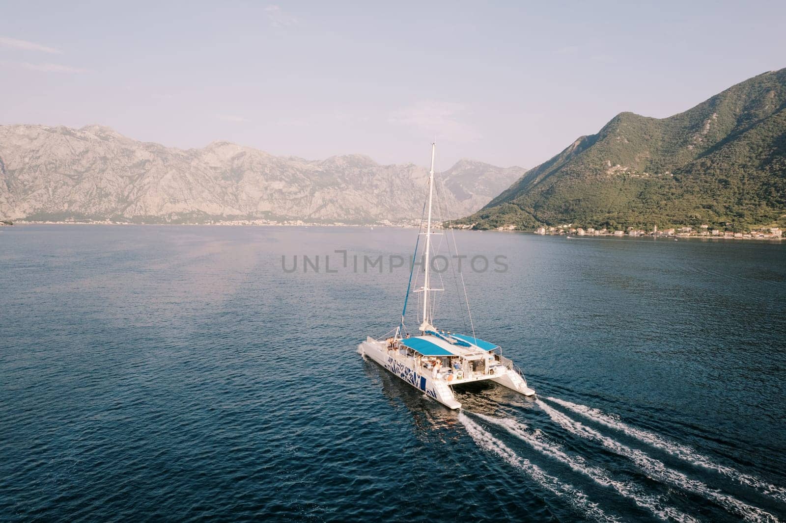 Large passenger sailing catamaran floats on the sea along the mountains. Drone. High quality photo