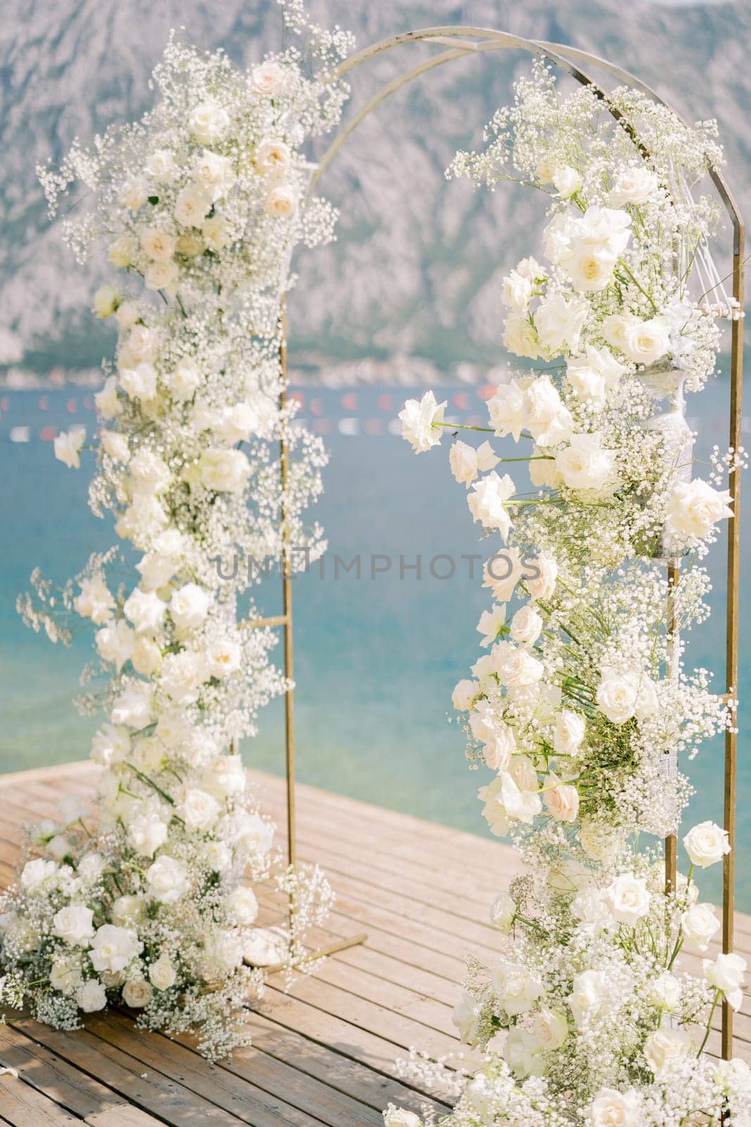 Wedding arch decorated with white flowers stands on the pier. Side view. High quality photo