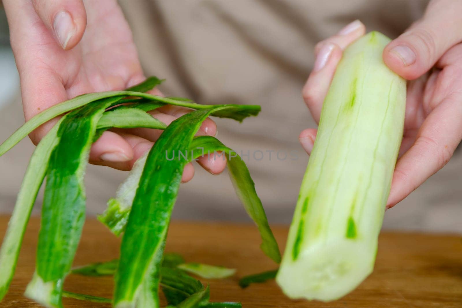 Close-up of a woman's hand peeling a cucumber. Peeling cucumber skins for salads or just to eat. High quality photo by SERSOL