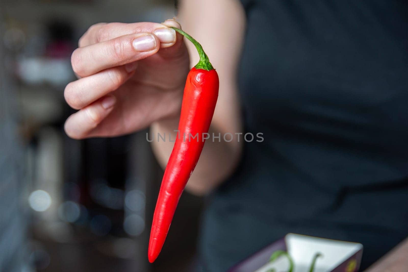 Woman's hand holding chili pepper close-up. Start cooking the spicy soup. High quality photo. by SERSOL