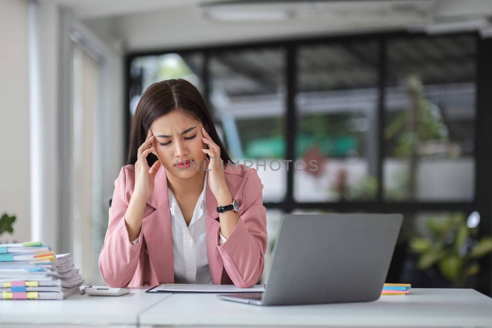 Young businesswoman feeling tired and bored while working for long hours in office by wichayada