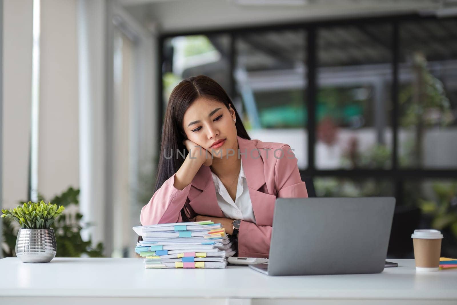 Young businesswoman feeling tired and bored while working for long hours in office.