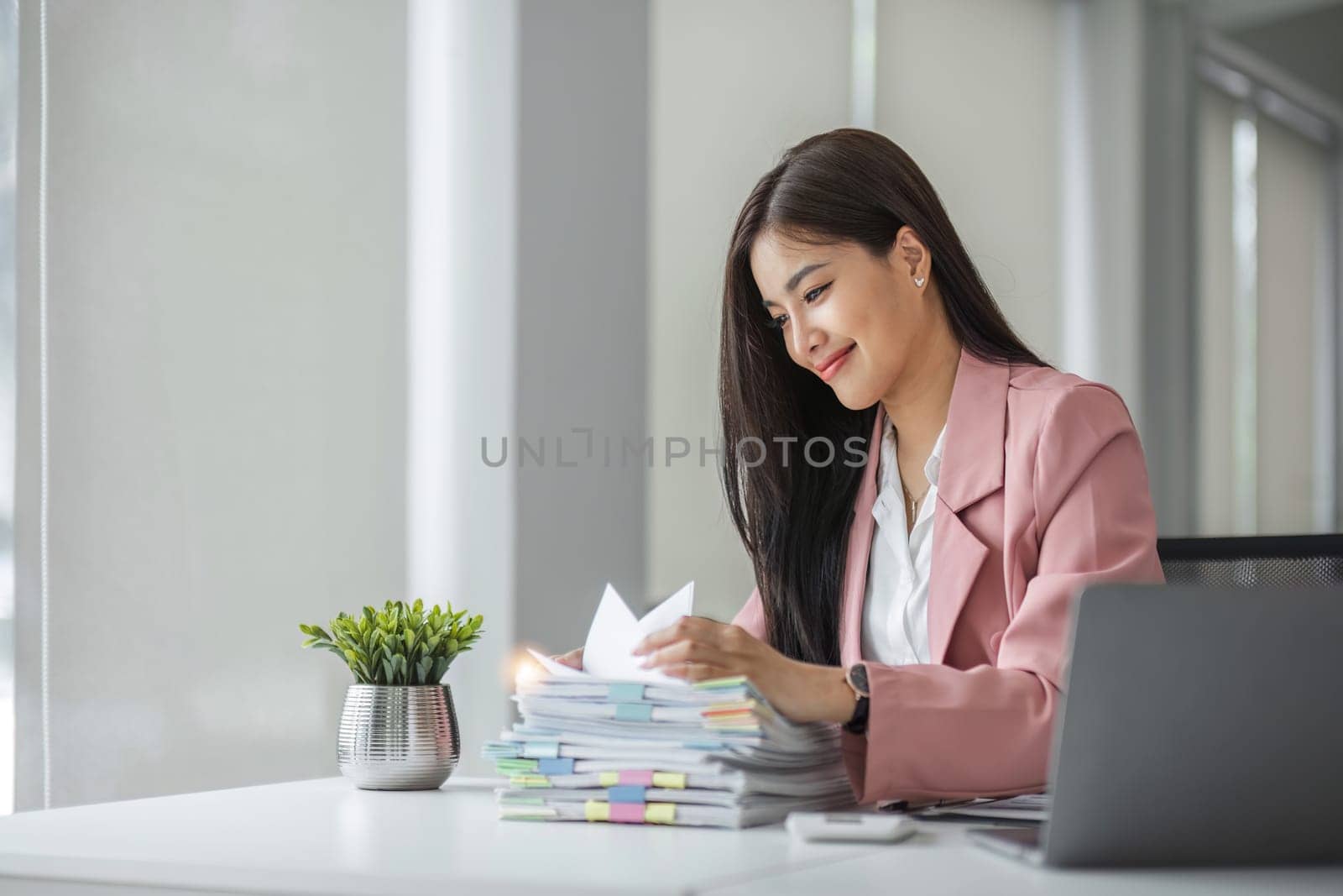 A happy businesswoman sits and checks her recently completed job information..