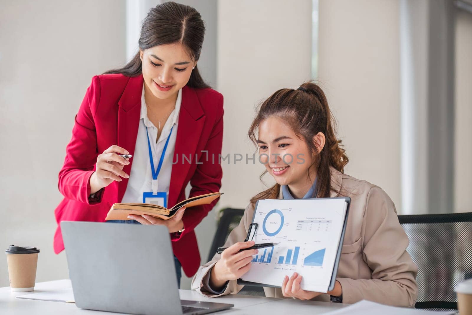 Two business women are discussing and exchanging knowledge on graphs and finance data..