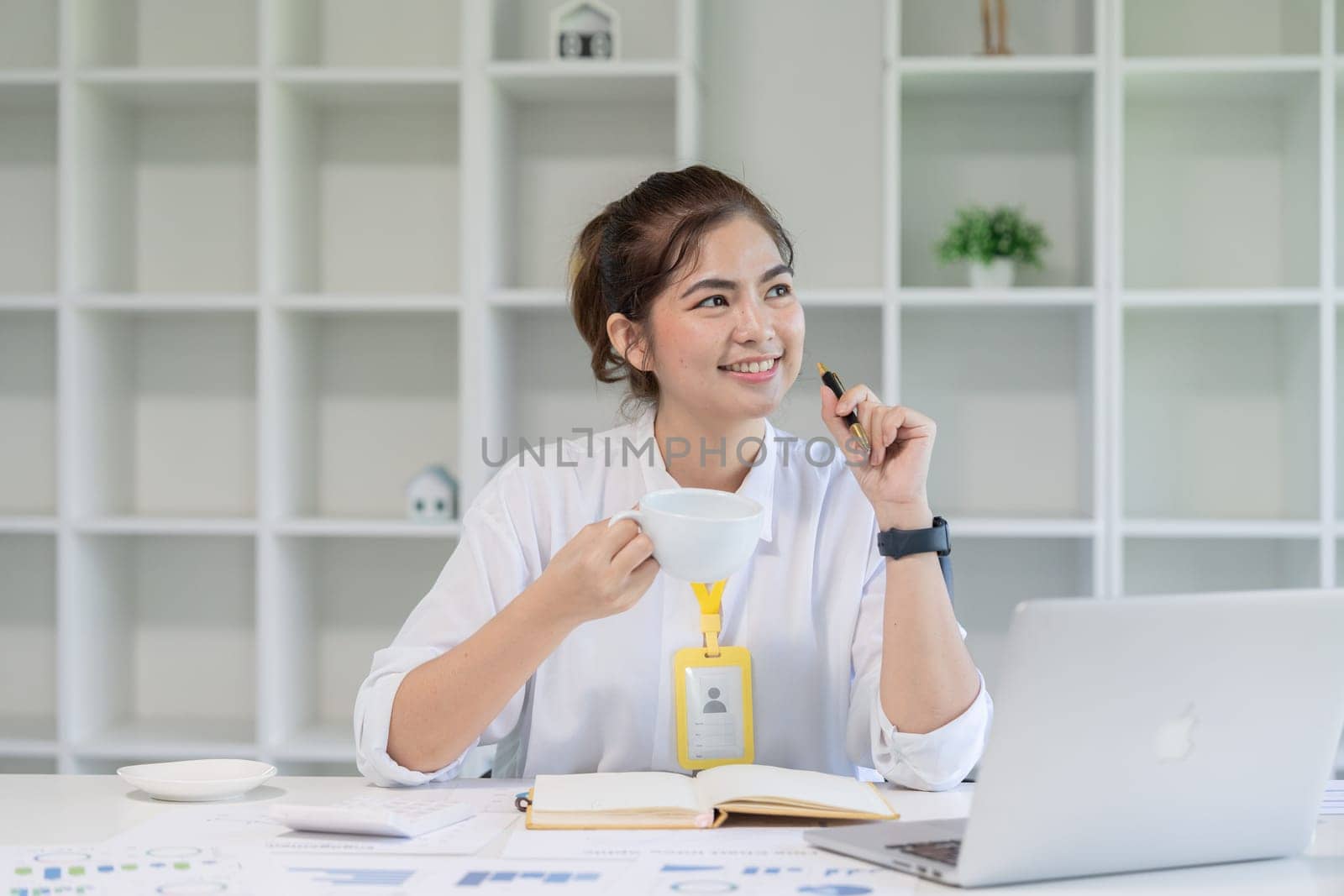 Young businesswoman enjoying her coffee while working laptop at home office.