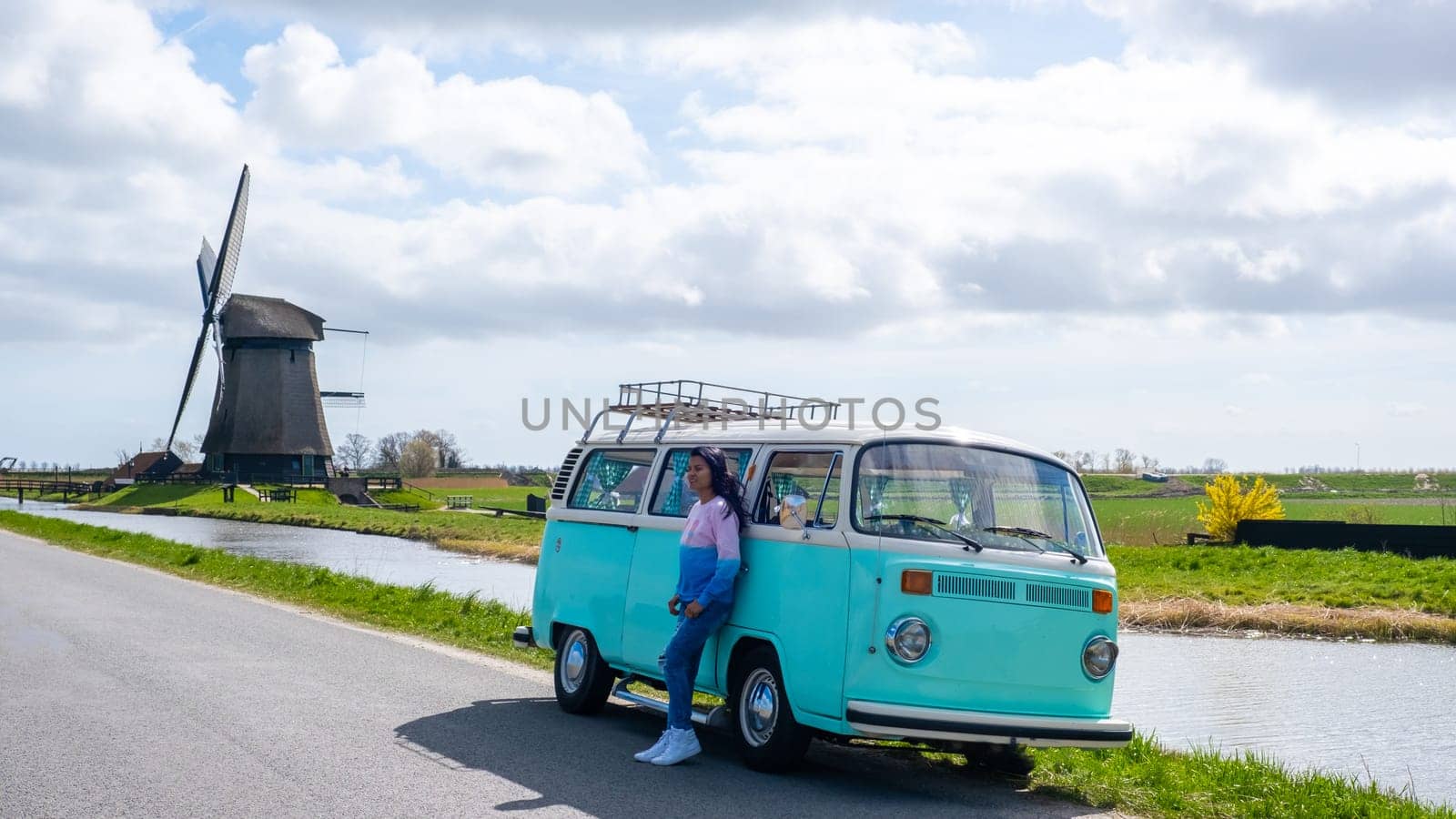 couple doing a road trip with an old vintage car in the Dutch flower bulb region with tulip fields by fokkebok