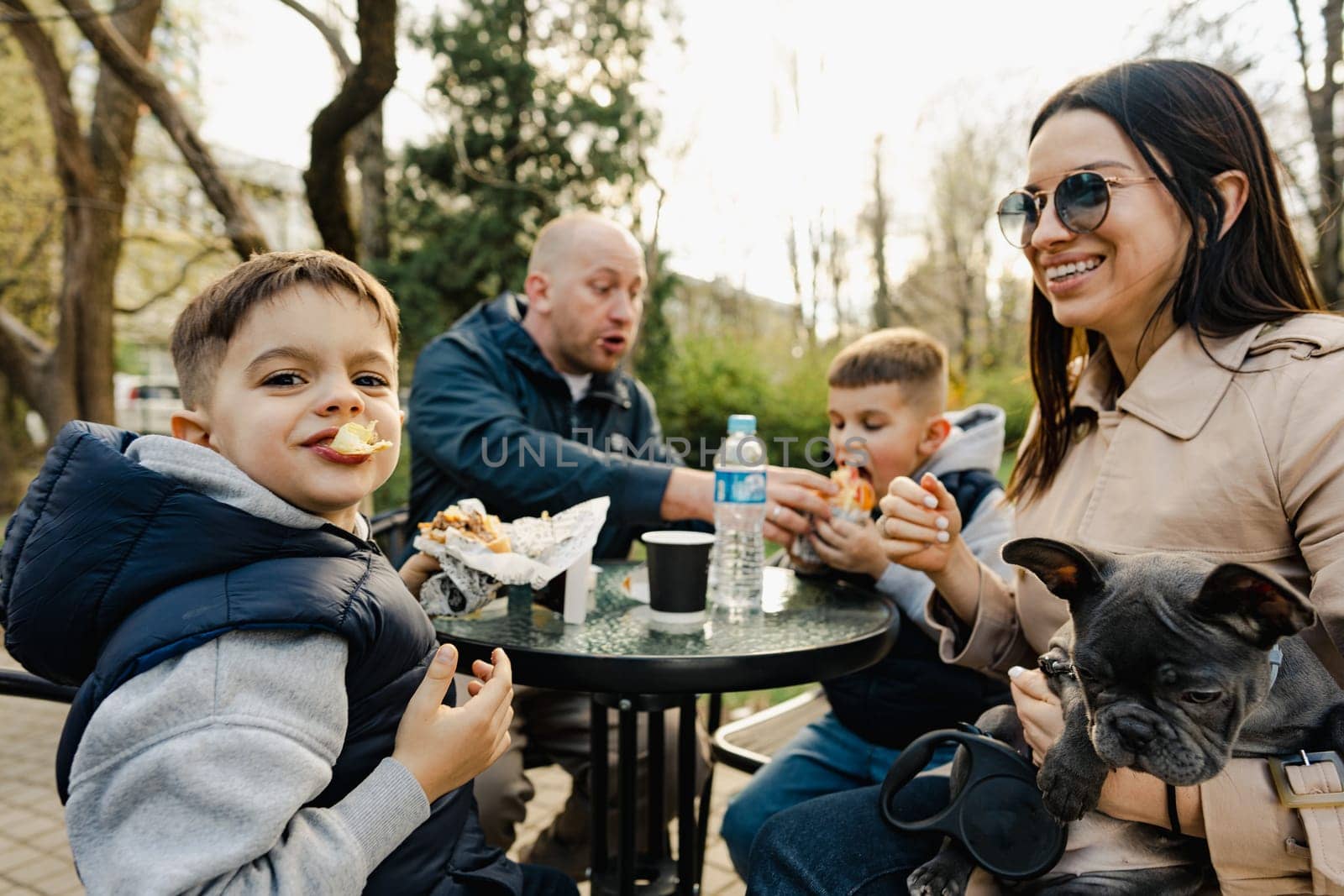 Happy family with two kids having a sancak at outdoor cafe on autumn day in park