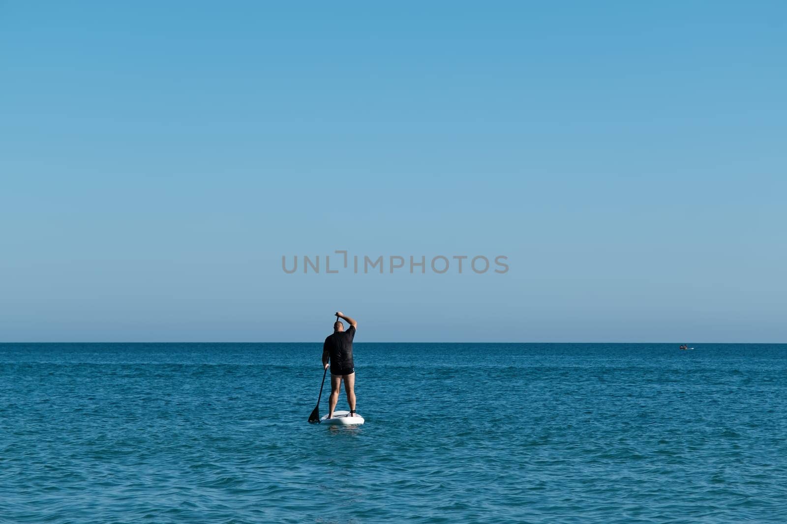 Caucasian man on paddle board in the sea by NataliPopova