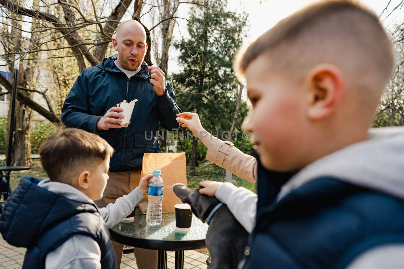 Happy family with two kids having a sancak at outdoor cafe on autumn day in park