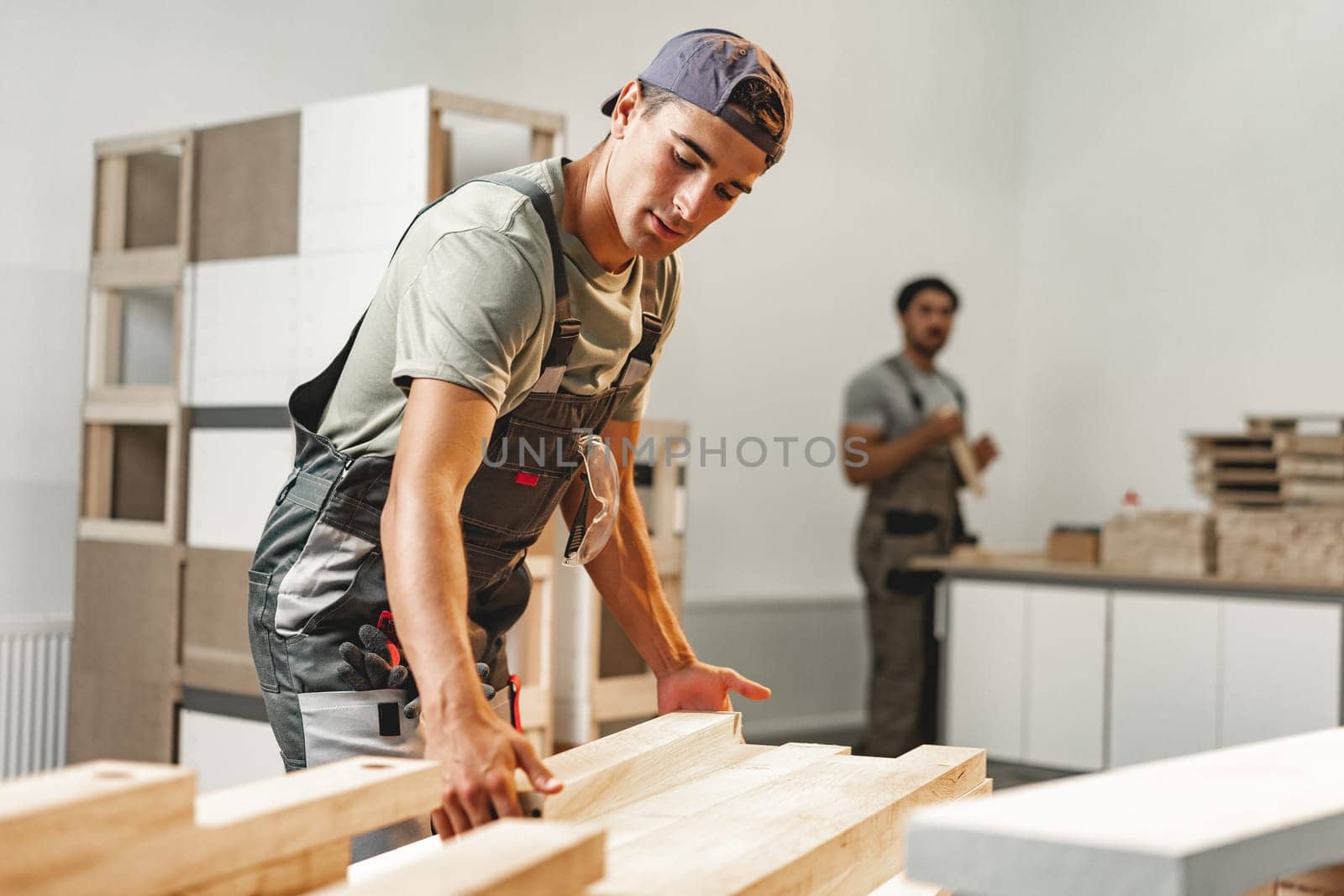 Young carpenter man looking and choosing wood plank at workshop in carpenter wood factory close up