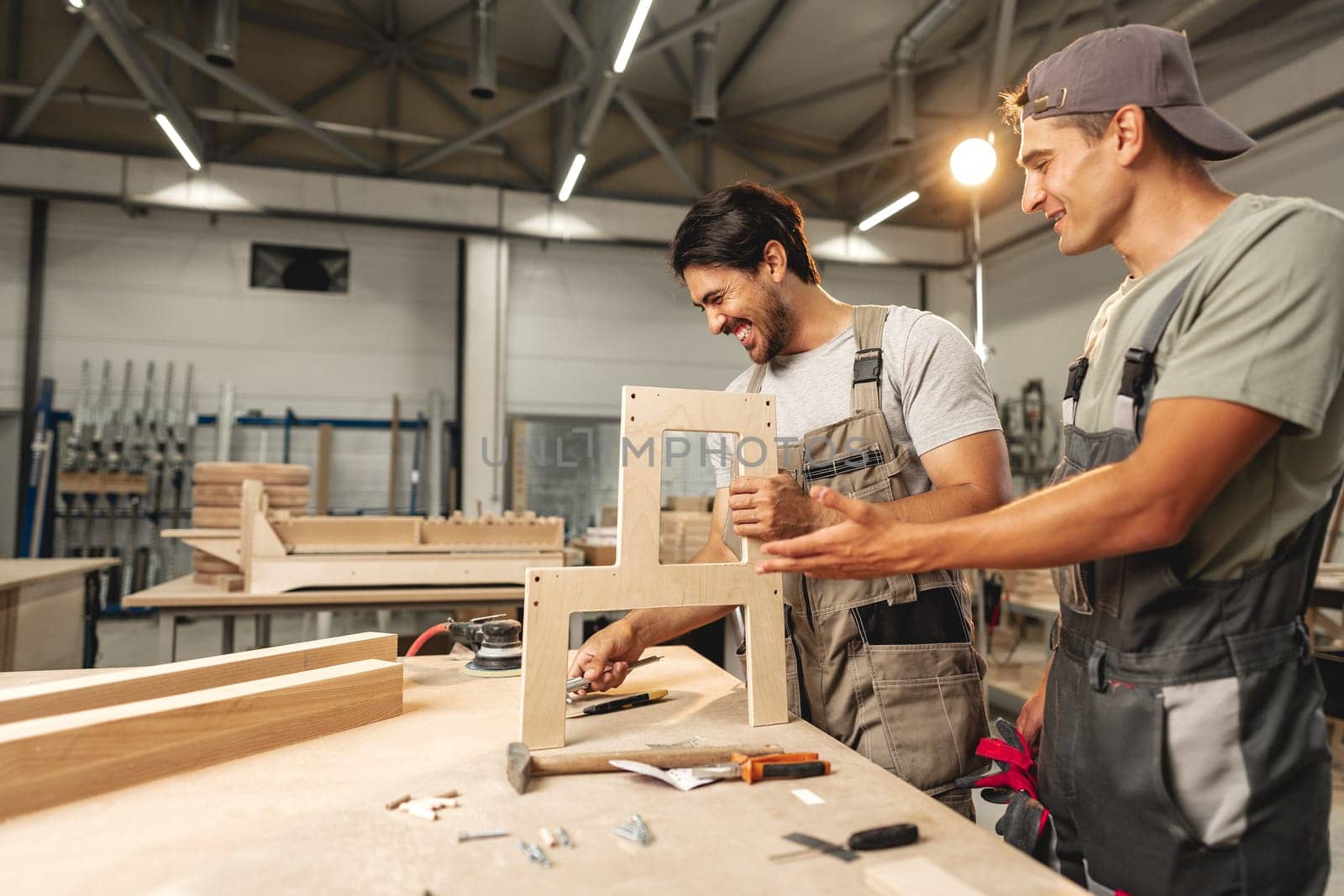 Two young men carpenters making furniture in warehouse of wood factory by Fabrikasimf