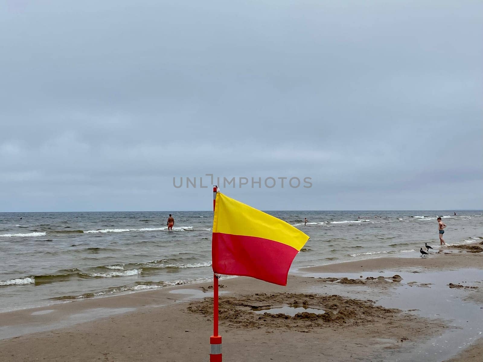 A Yellow and red beach flag, warning flag, lifesaving surf flag, rainy day in the beach, beach storm attention. High quality photo