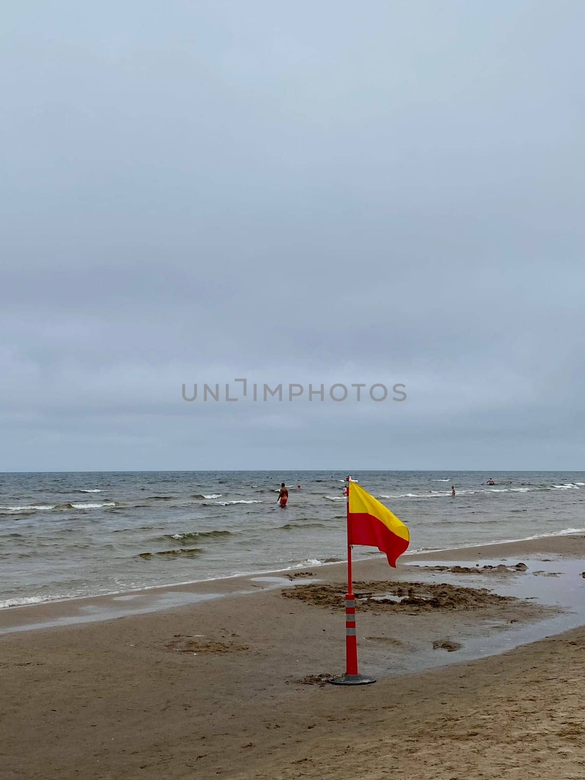 A Yellow and red beach flag, warning flag, lifesaving surf flag, rainy day in the beach, beach storm attention. High quality photo