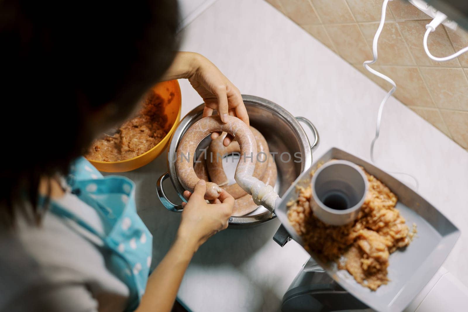 Housewife fills the intestines with minced meat on an electric meat grinder. High quality photo