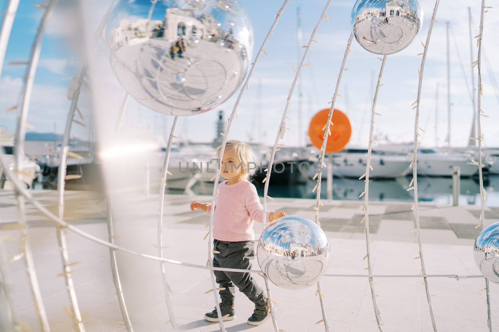 Little girl walks near a Christmas installation with mirror balls. High quality photo