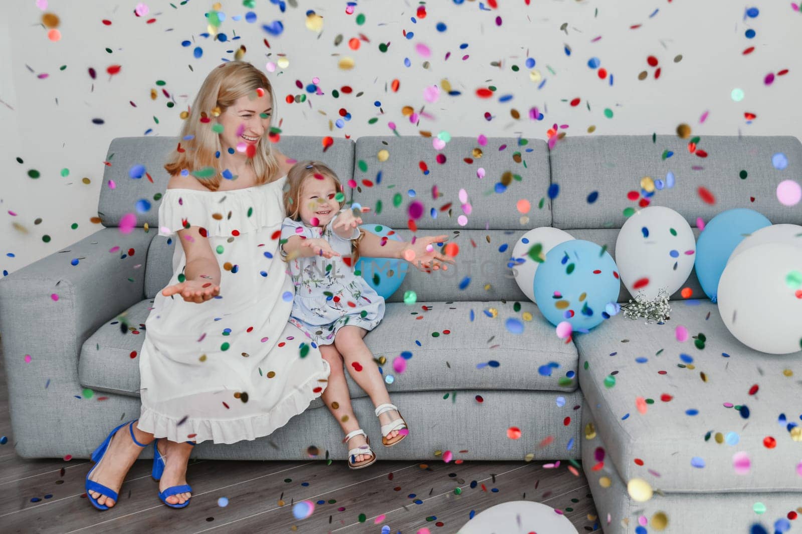 Mother and daughter celebrate birthday with ballons and confetti. by Godi