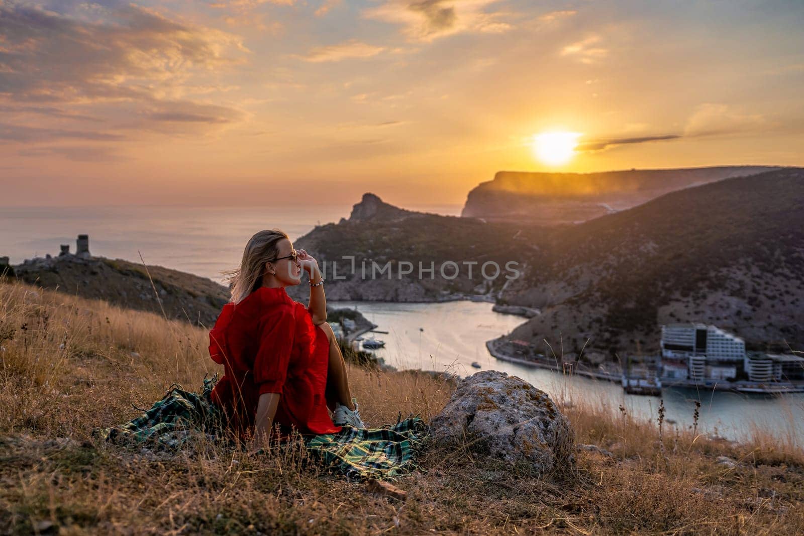 Woman sunset sea mountains. Happy woman siting with her back on the sunset in nature summer posing with mountains on sunset, silhouette. Woman in the mountains red dress, eco friendly, summer rest by Matiunina