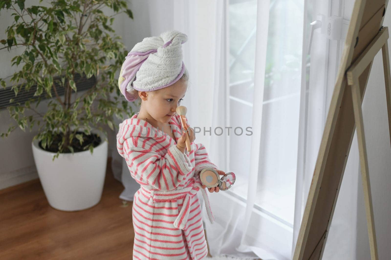 Little girl with a towel on her head doing makeup