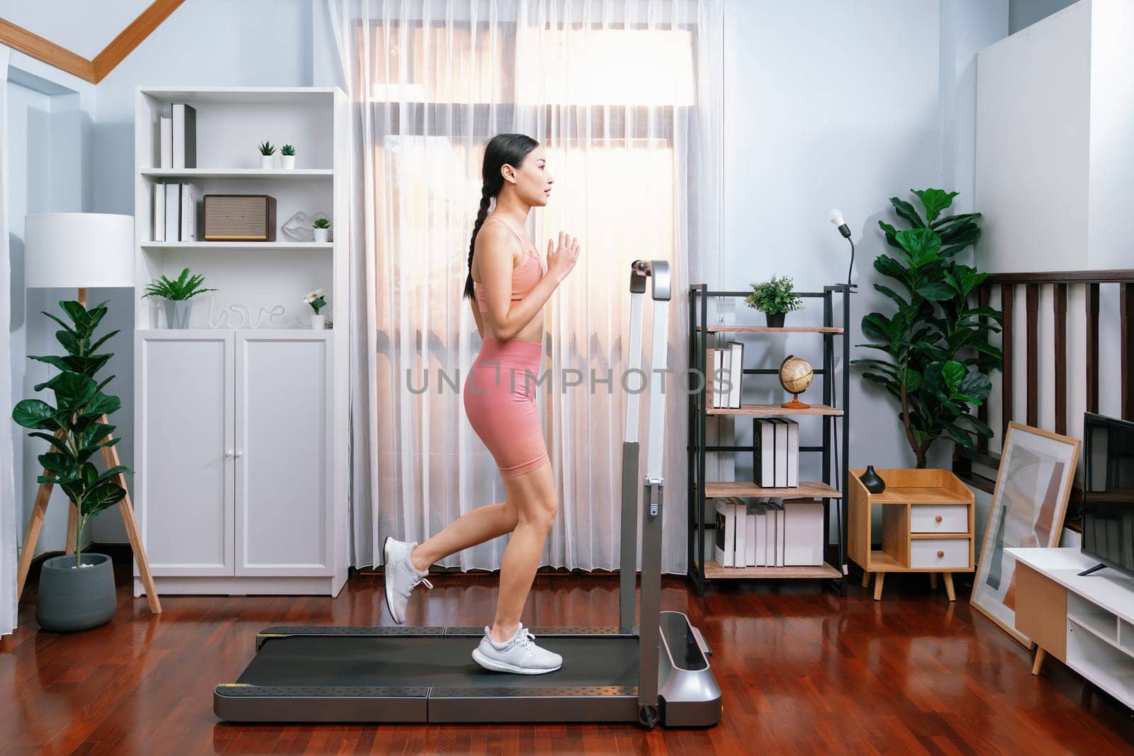 Energetic and strong athletic asian woman running at home. Vigorous by biancoblue