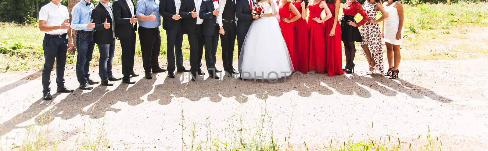Full length portrait of happy bride and groom standing with guests in garden