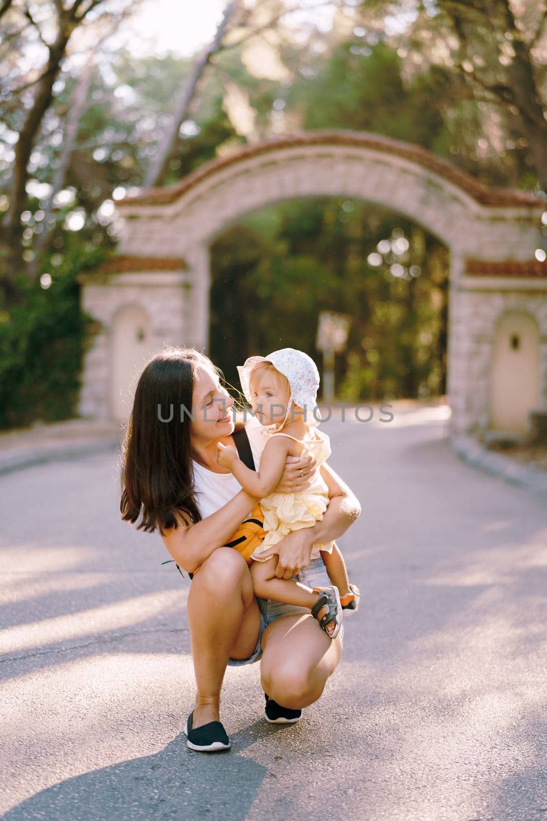 Mom is squatting with a little girl in her arms. High quality photo