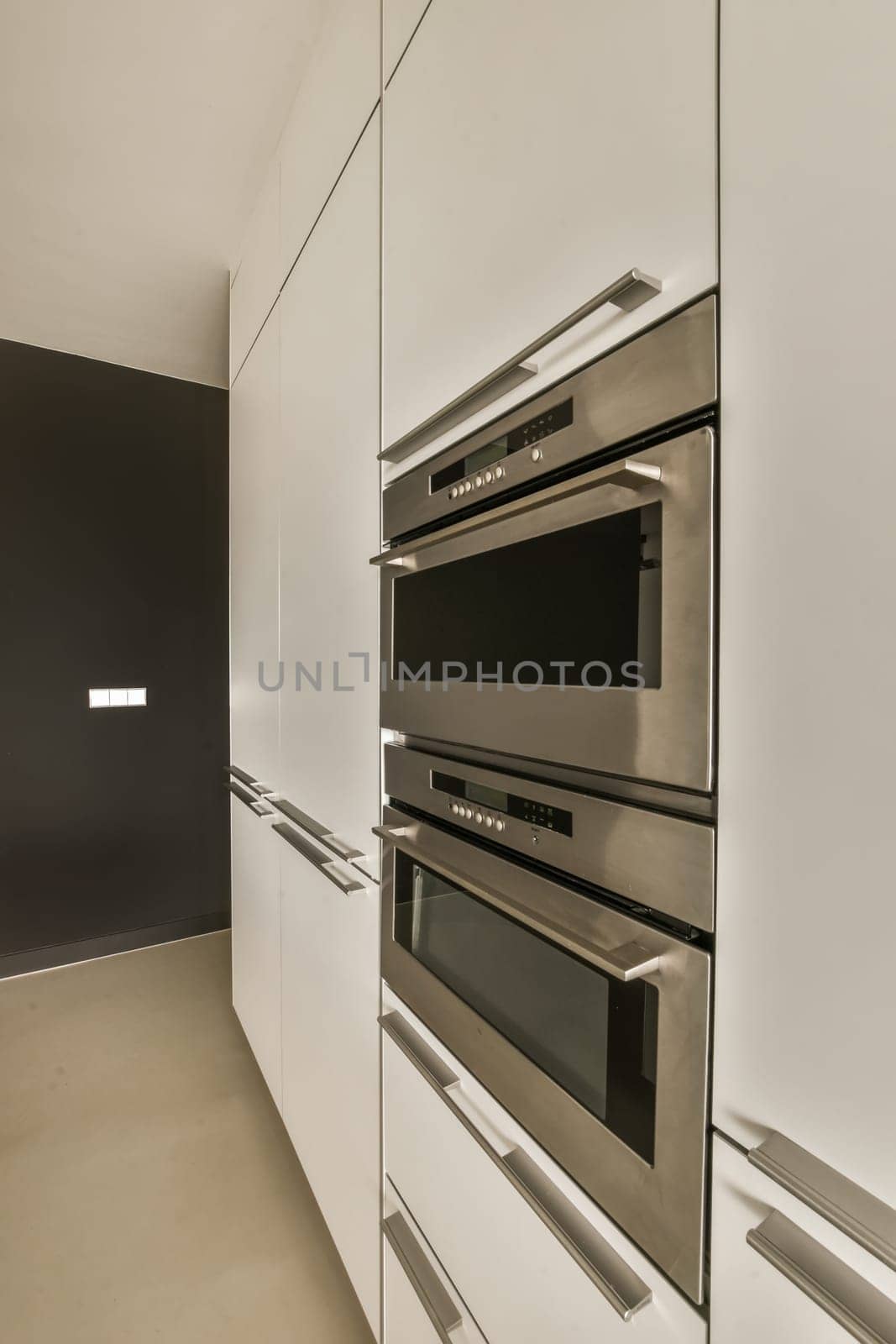 a kitchen with a stainless steel oven and white cabinets by casamedia