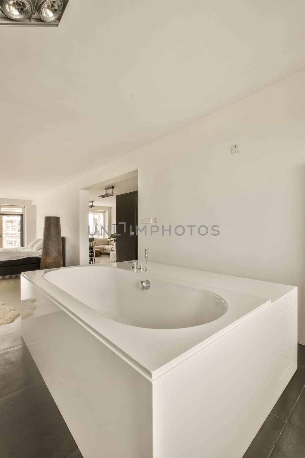 a white bathroom with black tile on the floor and an open door leading to another room in the back wall