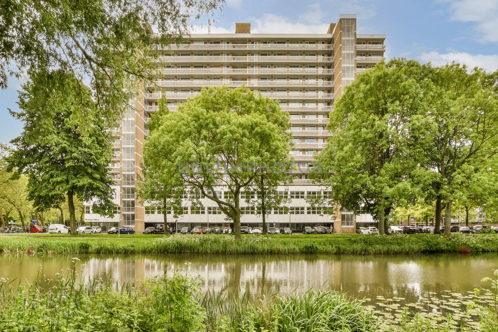 a view of an apartment building from across a pond by casamedia