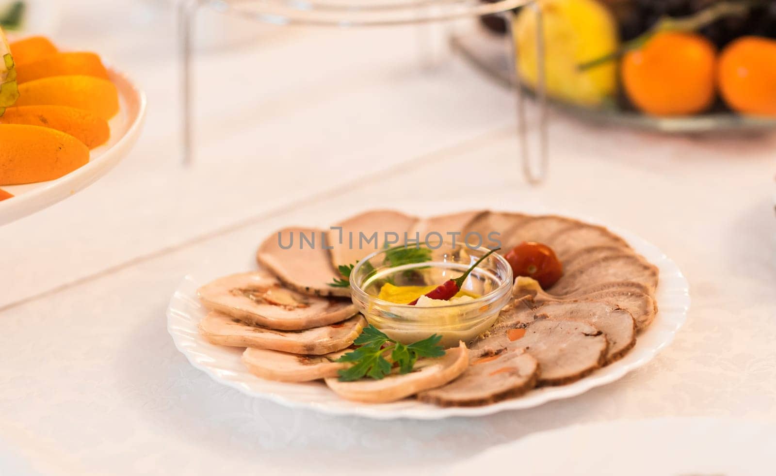 platter of sliced ham,salami and cured meat with vegetable decoration on festive table.