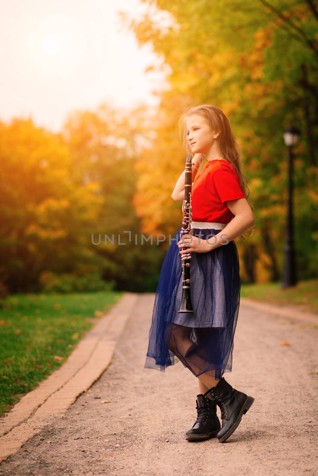 Young attractive girl playing clarinet in fall park