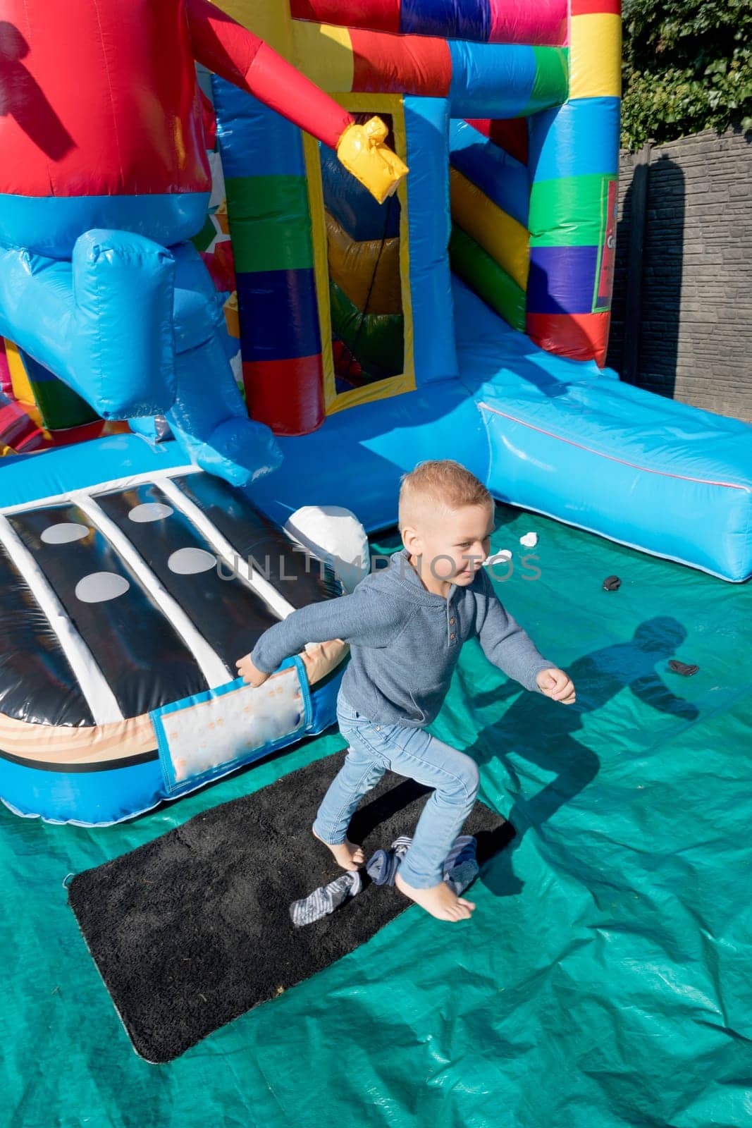 blond boy Child jumping on a colorful trampoline in the park, running away from friends and pursuers to a secret place, Portrait of a happy child High quality photo