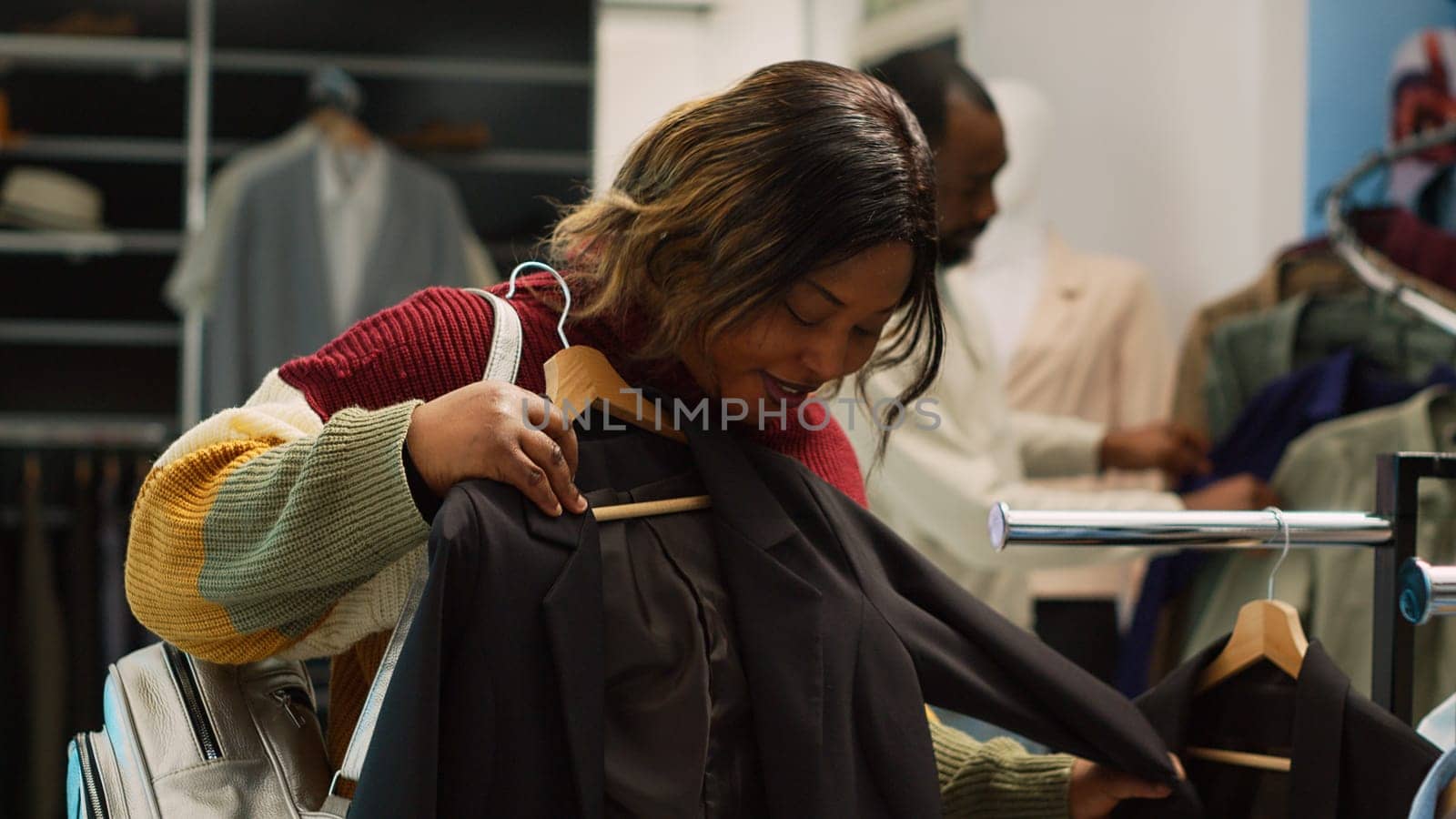 Female shopper taking formal clothes from hangers to increase wardrobe in department store. Young woman looking to buy new fashion collection, analyzing merchandise in boutique. Handheld shot.