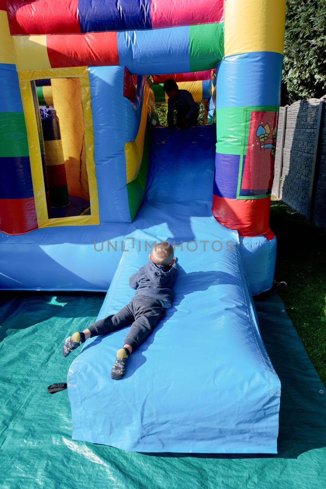 blond boy Child jumping on a colorful trampoline in the park, running away from friends by KaterinaDalemans