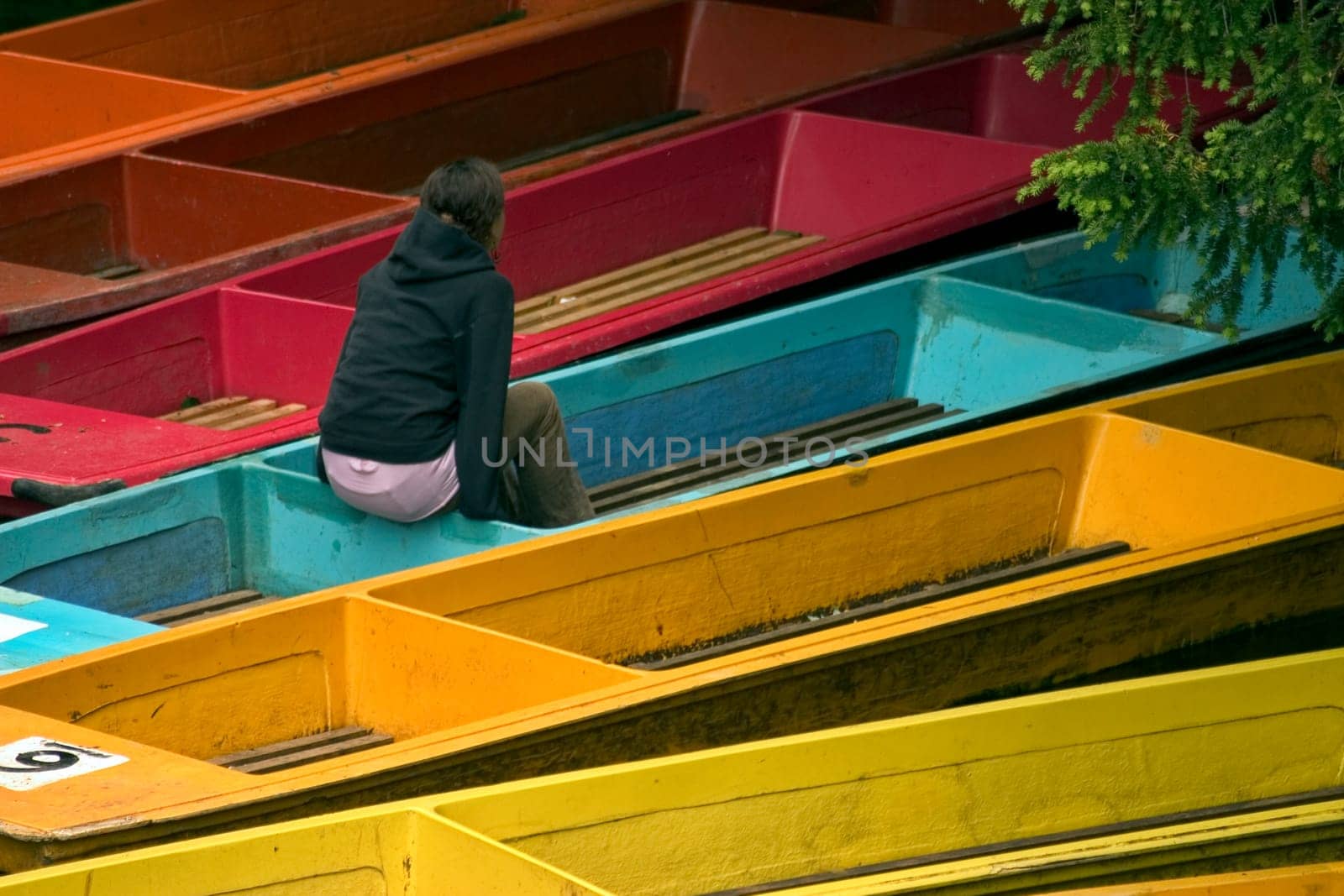 Girl sitting on her own on punt among other colourful punts.