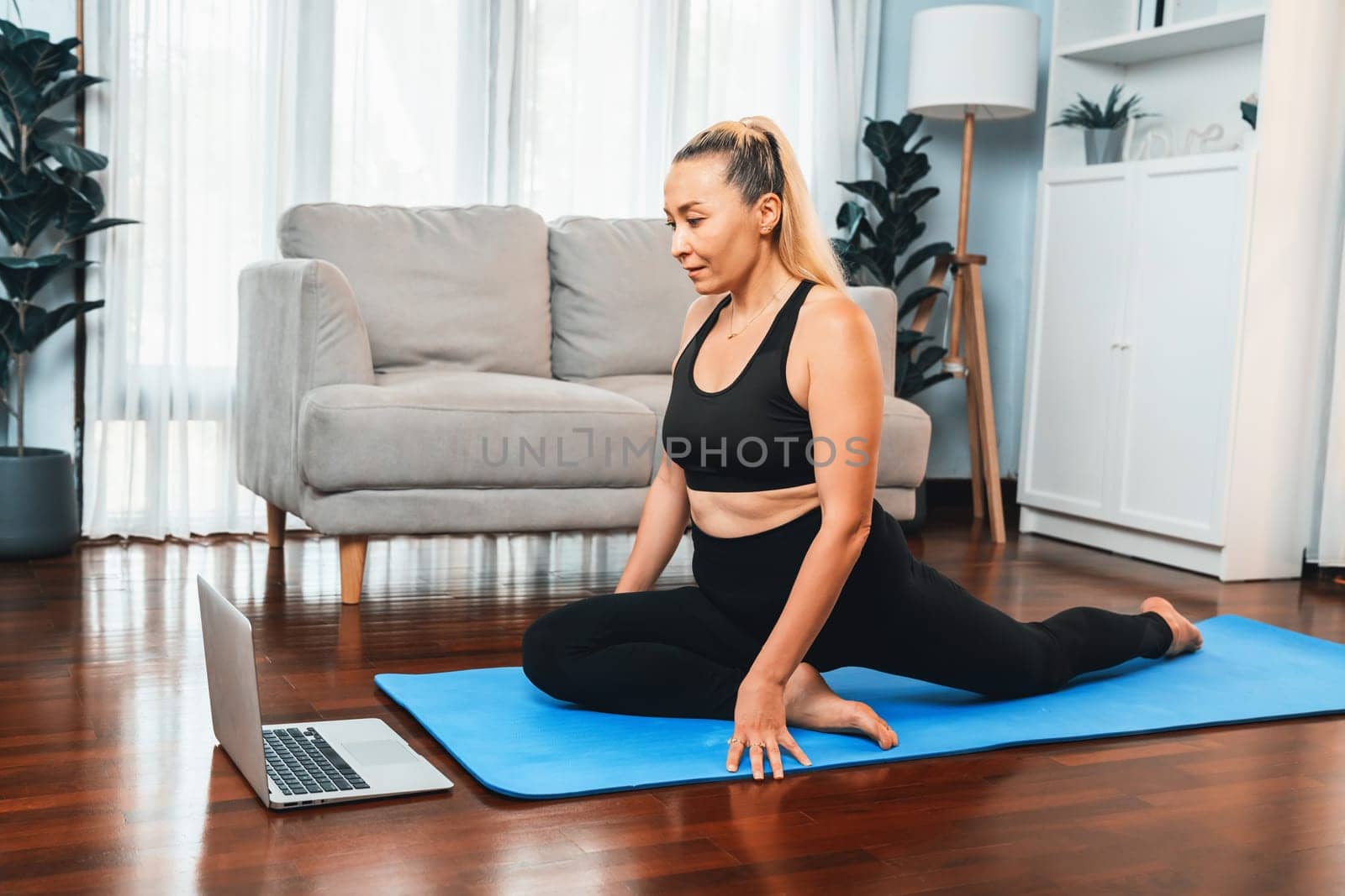 Senior woman in sportswear being doing yoga in meditation posture on exercising mat at home. Healthy senior pensioner lifestyle with peaceful mind and serenity. Clout